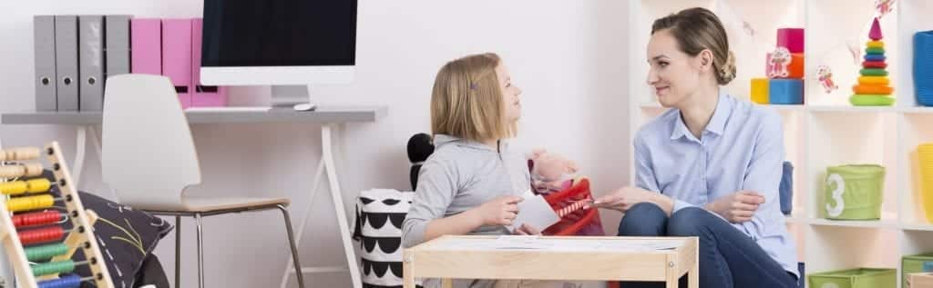 Speech therapist working with young girl at child sized desk.